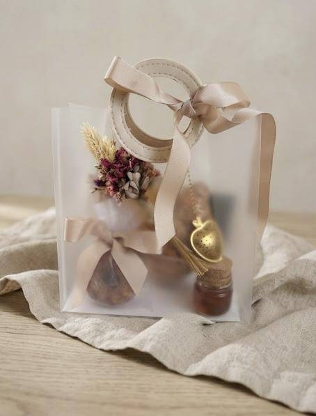 Sacola PVC fosca A Moça do Pão com arranjo floral e itens artesanais